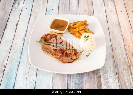 Steak de bœuf avec poivre et garniture de riz blanc et frites maison sur une assiette blanche Banque D'Images