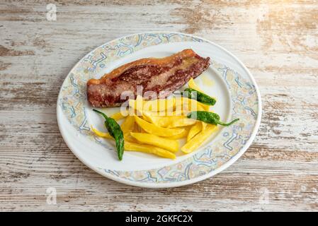 Entrecote de bœuf sur une assiette avec des pommes de terre frites et des poivrons padron Banque D'Images