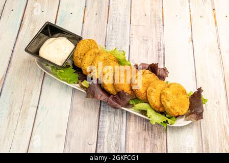 Plateau blanc allongé rempli de boules de falafel sur un lit de laitue et accompagné d'une sauce Banque D'Images