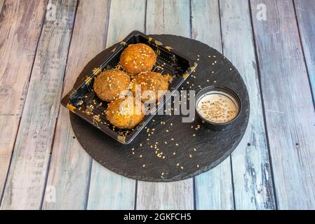 Boulettes de falafel frites avec sauce et graines de sésame présentées dans un récipient en plastique pour livraison à domicile Banque D'Images