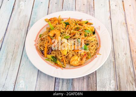 nouilles de riz chinoises aux crevettes décorées sautées, légumes wok et oignon rouge sur plaque blanche Banque D'Images