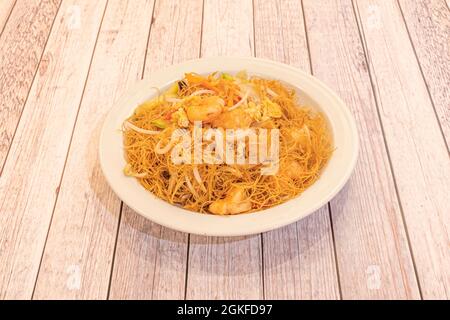 Fines nouilles de riz chinoises aux crevettes, pousses de haricots, oignons et omelettes avec légumes sautés sur une assiette blanche Banque D'Images