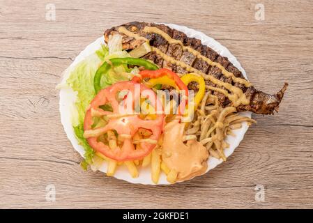 Plat de poisson avec salade, pommes de terre, oignons et sauce typique de l'Afrique subsaharienne Banque D'Images