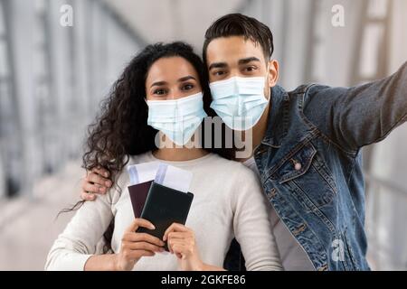 Voyage Selfie. Jeune couple arabe à masques médicaux prendre des photos à l'aéroport Banque D'Images