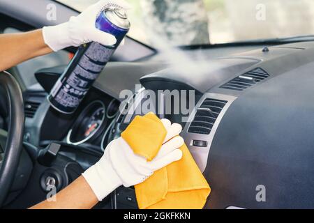 Services d'entretien d'intérieur de voiture. Un nettoyant pour plastique et un chiffon dans la main du nettoyant. Nettoyage de l'intérieur de la voiture. Entreprise de nettoyage Banque D'Images