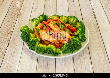 Crevettes grillées au piment fort, morceaux de poivrons verts et rouges et brocoli cuit sur une assiette blanche Banque D'Images