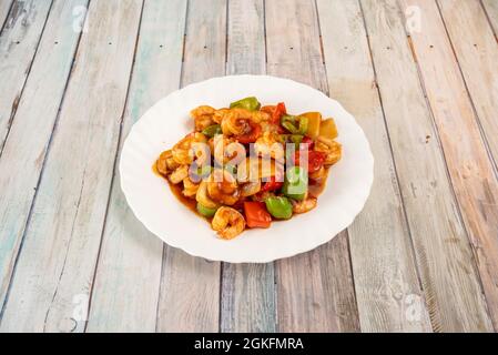 Ragoût de crevettes épicées asiatiques avec des morceaux de poivrons verts, rouges, oignons et bambou sur une assiette blanche Banque D'Images