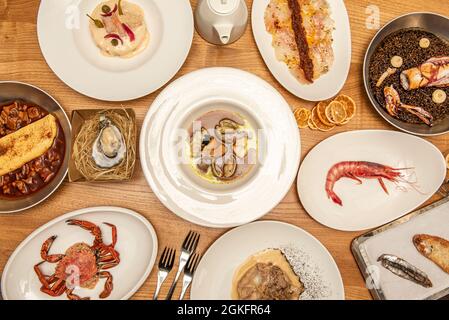 Plats espagnols populaires avec poisson et fruits de mer. Necora cuite, soupe de fruits de mer, pain grillé à la sardine, calmar avec riz, crevettes rouges, Huître galicienne. Banque D'Images