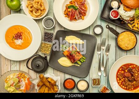 Ensemble de plats espagnols populaires. Saumon aux asperges, omelette à la pomme de terre, ragoût de pois chiches au chorizo, œufs cassés, salmorejo andalou, calmar romain Banque D'Images