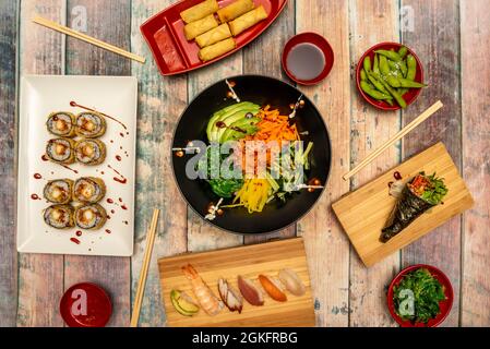 Vue de dessus de l'image de sushi et de la nourriture japonaise. Salade de wakame, gousses d'edamame avec flocons de sel de mer, rouleaux de crevettes, sushi de rouleau de dragon uramaki de crevettes, saumon Banque D'Images