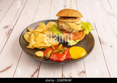 Hamburger de bœuf avec oignon frit et tomate, laitue, fromage fondu, frites, cornichons marinés, ketchup et moutarde Banque D'Images