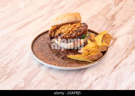 Hamburger de boucher avec un bon morceau de viande recouvert de sauce barbecue avec oignon croquant et quartiers de pommes de terre Banque D'Images