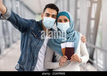 Heureux conjoints islamiques dans le visage médical masques prenant Selfie à l'aéroport Banque D'Images