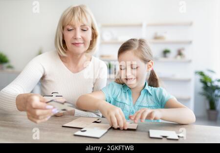 Portrait d'une femme mûre et d'une petite-fille heureuse en train de résoudre le puzzle Banque D'Images