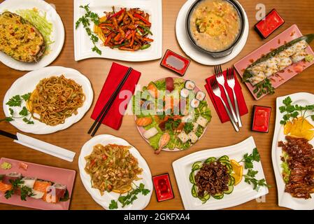 Sushis et plats chinois. Nigiri assortis, nouilles sautées aux crevettes, légumes sautés, nouilles udon, canard laqué, rouleau californien, carame Banque D'Images