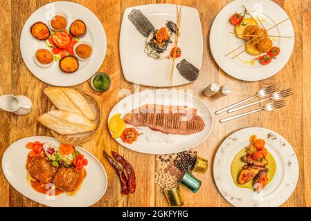 Ensemble de plats traditionnels espagnols. Calmar au riz blanc, pain de viande aux pommes de terre, entrecote grillé, ailes de barbecue aux tomates cerises Banque D'Images