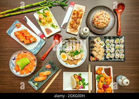 Vue de dessus image de plats asiatiques avec sashimi de saumon avec avocat, ramen de poisson et de légumes, plateaux variés d'uramaki et de maki, rouleau de Californie, s Banque D'Images