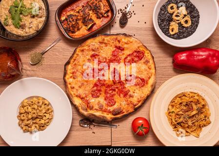 Ensemble de plats populaires de la cuisine italienne de base avec une pizza diavola, parmentier, arroz nero, pâtes de différents types avec poivre noir et huile d'olive Banque D'Images