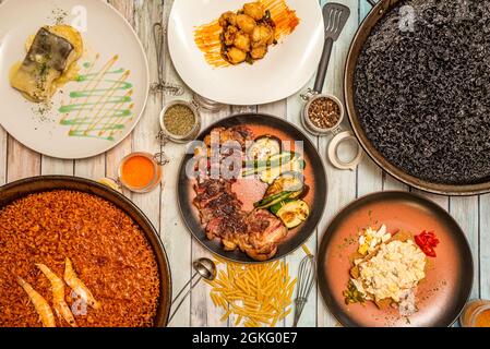 Vue de dessus des plats espagnols et des paellas. Paella de fruits de mer, paella de riz noir avec calmar, pil de morue, entrecote hachée, salade russe et conditionelle Banque D'Images