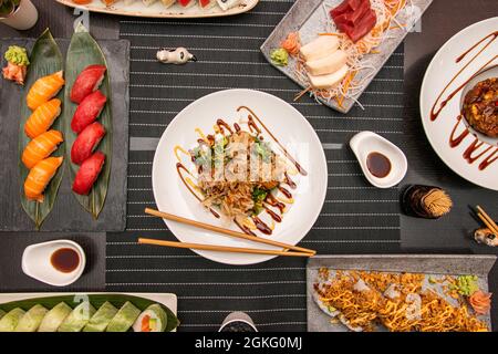 Vue de dessus des plats japonais. Sushi nigiri au saumon norvégien et au thon rouge, octopus takoyaki, sushi sashimi au poisson de bream, uramaki california rol Banque D'Images