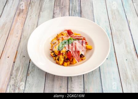 Plat espagnol typique de brisures d'œufs, avec pommes de terre frites maison, poivrons Padrón et tranches de jambon ibérique nourri aux glands sur fond de bois Banque D'Images