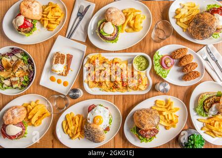 Ensemble d'assiettes de cuisine tex-mex, hamburgers et hors-d'œuvre sur une table en bois Banque D'Images