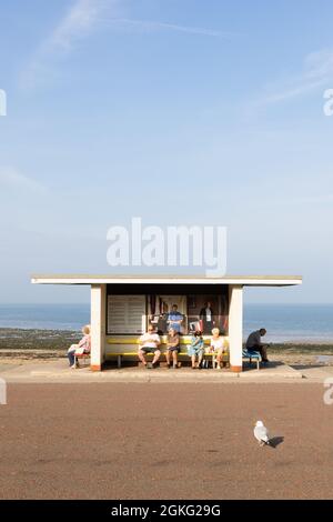 Llandudno, Conwy, Royaume-Uni, 6 septembre 2021 : personnes assises au soleil dans un abri sur la promenade qui longe la rive nord de Llandudno. Banque D'Images
