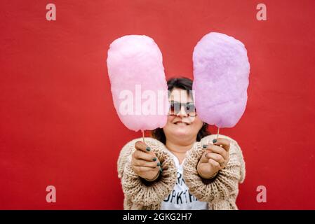 Femme avec deux bonbons en coton dans ses mains, elle porte des lunettes noires. Copier l'espace Banque D'Images