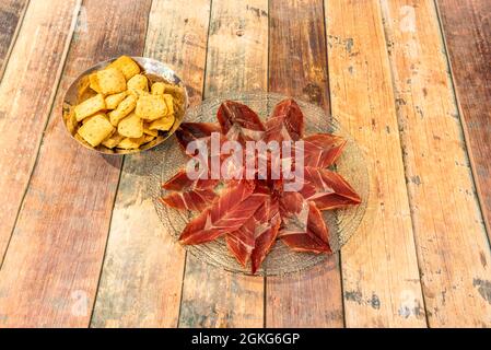 Portion de jambon ibérique nourri au gland sur une plaque en verre transparent avec des rhumes sur une table en bois Banque D'Images