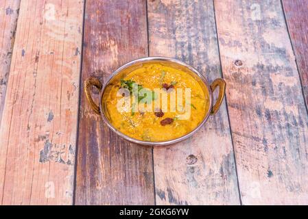 Poulet doux, korma, curry jaune avec raisins secs, coriandre et noix de coco râpée sur table en bois Banque D'Images