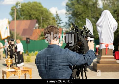 L'opérateur vidéo est en cours de prise de vue. L'opérateur se tient près de la caméra vidéo. Le travail de la chaîne de télévision. L'homme prend des photos. Banque D'Images