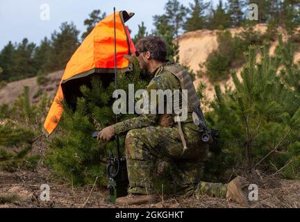 Un soldat de la Force terrestre canadienne des Royal Canadian Dragoons, 2e Groupe-brigade mécanisé du Canada, radio se rendre dans une zone d'atterrissage au début de la matinée du 16 avril. L'unité était en cours d'exercice conjoint avec le 3e Bataillon, 1re Brigade d'aviation de combat, 1re Division d'infanterie, pour dégager la zone de l'ennemi dans la région montagneuse de la frontière boisée près de Lielvarde, Lettonie. Banque D'Images