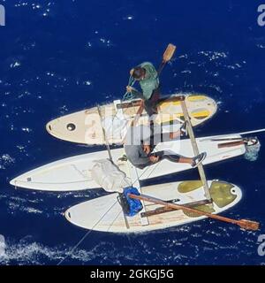 Deux migrants cubains à bord de paddleboards flottant à environ 70 milles au sud de Key West, Floride, le 16 avril 2021. Les migrants ont été embarqués par un bon Samaritain et rapatriés à Cuba par l'équipage du Cutter Charles Sexton de la Garde côtière. (. Banque D'Images