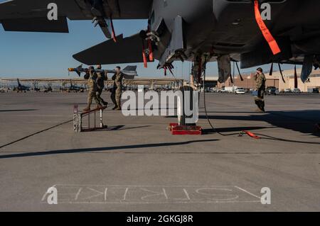 Les aviateurs du 757e Escadron de maintenance d'aéronefs portent une munition d'entraînement à charger sur un F-15 Strike Eagle lors d'une équipe de chargement de la compétition de quart à la base aérienne de Nellis, Nevada, le 16 avril 2021. Plusieurs équipes de chargement d'armes ont été classées en fonction de la rapidité, de la sécurité et de la compétence de chargement et de déchargement des munitions sur leurs aéronefs respectifs. Banque D'Images