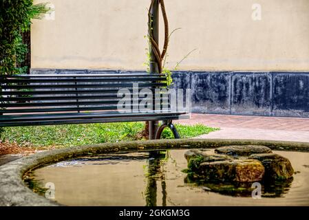 un banc dans un parc public en face d'un étang de poissons rouges Banque D'Images