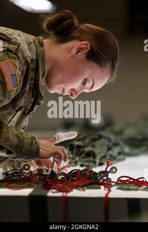 Sgt. Emilee Rolins, une truche de parachute de la 403e équipe de soutien de Rigger de la Garde nationale de Caroline du Nord, inspecte les cordeaux de parachute pour les dommages à fort Bragg, en Caroline du Nord, le 17 avril 2021. Le 403e prend en charge les unités de garde de la Caroline du Nord en fournissant des parachutes de fret et des parachutes personnels pour les opérations aériennes. Banque D'Images