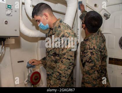 OCÉAN PACIFIQUE (17 avril 2021) — U.S. Marine corps lance Cpl. Andrew Cardenas, de Phoenix, à gauche, et lance Cpl. Pedro Alvarado, de Los Angeles, à droite, nettoyer un passage à bord du quai de transport amphibie USS Portland (LPD 27), avril 17. Portland mène actuellement des opérations de routine dans la troisième flotte des États-Unis. Banque D'Images