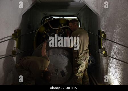 Sergent d'état-major Dustin Primo, à gauche, 341e Escadron de maintenance des missiles Chef de l'équipe de traitement des missiles et principal Airman Dylan Funkhouser, technicien de traitement des missiles, placez solidement un couvercle sur l'avant du surpresseur de niveau 1 du missile balistique intercontinental Minuteman III le 20 avril 2021, à l'installation de traitement des missiles de la base aérienne de Malmstrom, Le couvercle est placé après que la moitié du missile a roulé d'un transporteur à l'autre. Banque D'Images