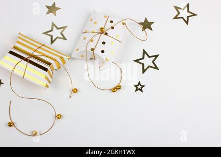 Deux boîtes-cadeaux avec cloches dorées et étoiles sur fond blanc. Joyeux Noël et concept du nouvel an. Carte de vœux. Copier l'espace. Pose à plat. Banque D'Images