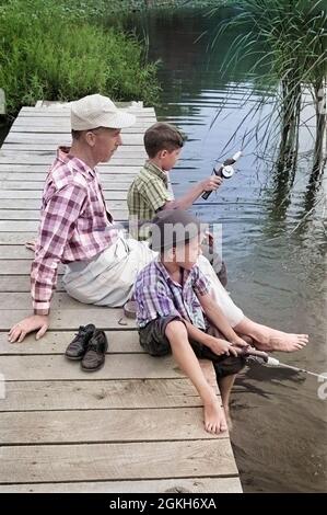 PÈRE DES ANNÉES 1950 AVEC DEUX FILS ASSIS SUR LE QUAI DE PÊCHE ENSEMBLE À L'EXTÉRIEUR PAR L'ÉTANG - A1979C LAN001 HARS ENSEIGNEMENT DE LA NOSTALGIE FRÈRE VIEILLE MODE 1 JUVÉNILE PÔLE POND VACANCES FILS FAMILLES STYLE DE VIE PARENTS FRÈRES RURAUX GROGNUP COPIE ESPACE AMITIÉ DEMI-PERSONNES LES HOMMES DE QUAI ADULTE SERENITY ROD S'ATTAQUENT AUX PÈRES ANGLER B&W PARENT UNIQUE PATERNEL RELÂCHE LES PÔLES TEMPS HORS PATERNITÉ ACTIVITÉ BONHEUR PÊCHE POTEAU GRAND ANGLE HOBBY ÉTÉ SAISON PÊCHEURS VOYAGE ESCAPADE COLLAGE DADS RÉCRÉATION TRIO PIEDS NUS VACANCES LOISIRS PÊCHE FRÈRE ECHAPPEZ-VOUS À LA CANNE À PÊCHE Banque D'Images