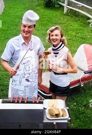 ANNÉES 1950, ANNÉES 1960, UN COUPLE DE GRILLADES À L'ARRIÈRE-COUR REGARDANT L'APPAREIL PHOTO CUISINER HOT DOGS HOMME PORTANT UN TABLIER TOQUE ET SKEWED HOT DOG - C8205C DEB001 HARS BARBECUE ACTIVE CUISINIÈRE PAIRE ARRIÈRE-COUR RELATION VIEUX TEMPS ROULEAU NOSTALGIE BARBECUE ANCIENNE MODE 1 MENU GRILL BIENVENUE RIRE VACANCES SNACK STYLE DE VIE CHAISE MARIÉE CONJOINT ÉPOUX ADULTES MAISON VIE COPIE ESPACE DEMI-LONGUEUR SALON AMERICANA ALIMENTS SNACK B&W. PARTENAIRE OEIL CONTACT SNACKS LOISIRS CAMPING FOYER ACTIVITÉ GRILLER BONHEUR HOMMES LOISIRS PRÉPARER SNACK NOURRITURE FRANKFURTER QUALITÉ TEMPS RÉCRÉATION FÉMININE CHAISE LONGUE QUALITY BUN FRANK WIENER Banque D'Images