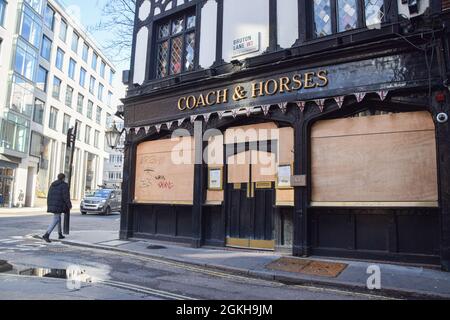 Un homme passe devant le pub Coach & Horses fermé et embarqué dans le centre de Londres pendant le confinement du coronavirus. Londres, Royaume-Uni 18 février 2021. Banque D'Images