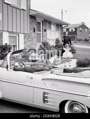 DANS LES ANNÉES 1950, UNE MÈRE ET UNE FILLE JOYEUSES SE SONT RÉJOUIEUSES DE S'ÊTRE FAIT PASSER POUR UN PÈRE À SON ARRIVÉE OU À SON DÉPART POUR TRAVAILLER OU POUR UN VOYAGE D'AFFAIRES À CHEVROLET VOITURE CONVERTIBLE - J8115 HAR001 HARS MOM VÊTEMENTS NOSTALGIQUE PAIRE LAISSE SUBURBAIN MÈRES CONVERTIBLE VIEUX TEMPS OCCUPÉ SURPRISE NOSTALGIE VIEUX MODE AUTO 1 ALLÉE JUVÉNILE STYLE VÉHICULE TRAVAIL D'ÉQUIPE FAMILLES JOIE STYLE DE VIE SATISFACTION FEMMES MAISONS MARIÉ CONJOINT ÉPOUX MAISON VIE COPIE ESPACE PLEINE LONGUEUR FEMMES FILLES PERSONNES AUTOMOBILE RÉSIDENTIEL HOMMES BÂTIMENTS TRANSPORT PÈRES ÂGE MOYEN B&W CHEVROLET PARTENAIRE SUCCÈS BONHEUR TÊTE ET ÉPAULES DÉCLENCHEMENT À ANGLE ÉLEVÉ ET AUTOS Banque D'Images