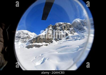 La fenêtre à bulles d'un hélicoptère CH-47F Chinook de la Compagnie B, 1er Bataillon, 52e Aviation Regiment offre une vue circulaire des montagnes de la chaîne de l'Alaska le 22 avril 2021. Les aviateurs de l'unité, également connus sous le nom de Sugar Bears, ont voyagé de fort Wainwright pour aider le Service des parcs nationaux à obtenir l'équipement et les fournitures nécessaires pour le camp de base au niveau de 7,200 pieds du glacier Kahiltna pour la saison d'escalade 2021 sur Denali, La plus haute montagne d'Amérique du Nord. (Photo de l'armée/John Pennell) Banque D'Images