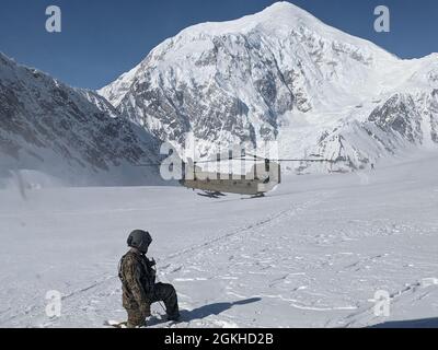 Un soldat de la Compagnie Bravo, 1er Bataillon, 52e Régiment d'aviation, basé à fort Wainwright, regarde comme un deuxième hélicoptère CH-47 Chinook atterrit sur le glacier Kahiltna, dans le parc national Denali, avec de l'équipement et des fournitures pour le service des parcs nationaux. L'unité fournit une aide annuelle pour les fournitures volantes au camp de base situé à 7,200 pieds d'altitude. Banque D'Images