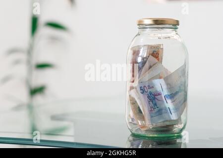 Argent, billets colombiens en pot de verre, sur table de verre, financier, épargne. Caisse d'argent, pot plein d'argent, concept d'économie d'argent, de planification et de contro Banque D'Images