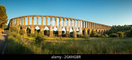 Vue panoramique de l'aqueduc de Pegões, près de la ville de Tomar au Portugal, avec un champ en premier plan, le ciel bleu en arrière-plan et la plaque Banque D'Images