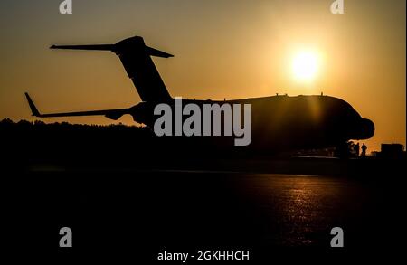 Le soleil se lève au-dessus d'un C-17 Globemaster III sur la ligne de vol à la base aérienne de Douvres, Delaware, le 23 avril 2021. Le C-17 Globemaster III est l'avion cargo le plus flexible pour entrer dans la force de transport aérien. L'avion peut effectuer des missions de transport aérien tactique et de chute d'air, ainsi que des portées de transport de patients ambulatoires pendant les évacuations aéromédicales. Banque D'Images