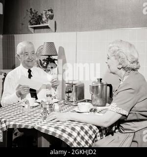 UN COUPLE ÂGÉ DES ANNÉES 1950 ASSIS À LA TABLE DE LA CUISINE AVEC DES TOASTS ET UN HOMME DU CAFÉ QUI OUVRE LE COURRIER DU MATIN SOURIANT TENANT LE CHÈQUE - S434 HAR001 HARS VIEILLE MODE 1 ASSURANCE COMMUNICATION GRILLE-PAIN STYLE DE VIE SATISFACTION FEMMES AÎNÉES CONJOINT ÉPOUX MAISON VIE COPIE ESPACE AMITIÉ DEMI-LONGUEUR FEMMES PERSONNES NAPPE HOMMES SENIOR HOMME SENIOR APPARTEMENT ADULTE B&W PARTENAIRE DU MATIN FEMME SENIOR BONHEUR OLDSTERS OLDSTER TOAST ET CAFETIÈRE RELATION AVEC LES AÎNÉS HOMME ÂGÉ DÎNER FEMME ÂGÉE SÉCURITÉ SOCIALE TOGETHERNESS ÉPOUSES NOIR ET BLANC RACE BLANCHE HAR001 OLD À LA MODE Banque D'Images