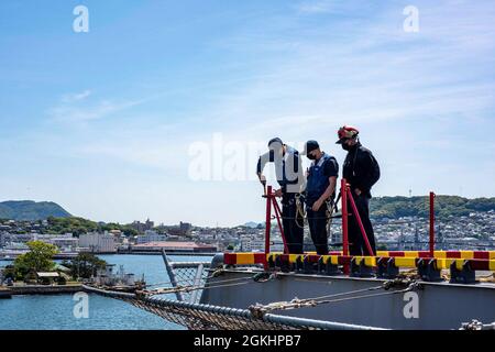 SASEBO (Japon) (le 26 avril 2021) des marins affectés au navire d’assaut amphibie déployé à l’avant USS America (LHA 6) installent des lignes de sauvetage sur l’élévateur du navire. L'Amérique, navire chef de file du America Amphiobie Ready Group, opère dans la zone de responsabilité de la 7e flotte des États-Unis afin d'améliorer l'interopérabilité avec les alliés et les partenaires et de servir de force de réaction prête à l'emploi pour défendre la paix et la stabilité dans la région Indo-Pacifique. Banque D'Images